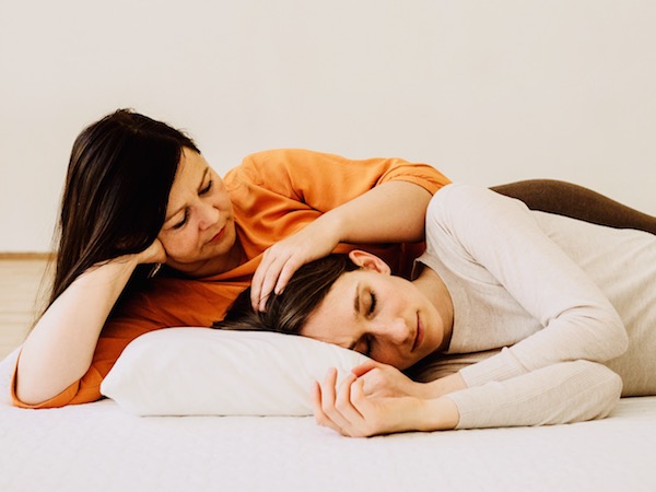 Achtsame Seitenlage zwischen Kuscheltherapeutin und Klientin, die sich sichtbar sicher und gehalten fühlt.