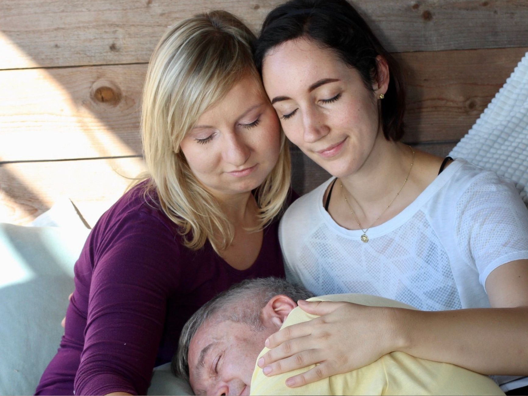 Teilnehmer:innen sinken sichtbar in Entspannung, während sie während einer Conscious Cuddle Experience liebevolle, klare Berührung empfangen – weiche Gesichtszüge, reguliertes Nervensystem, spürbare Geborgenheit.