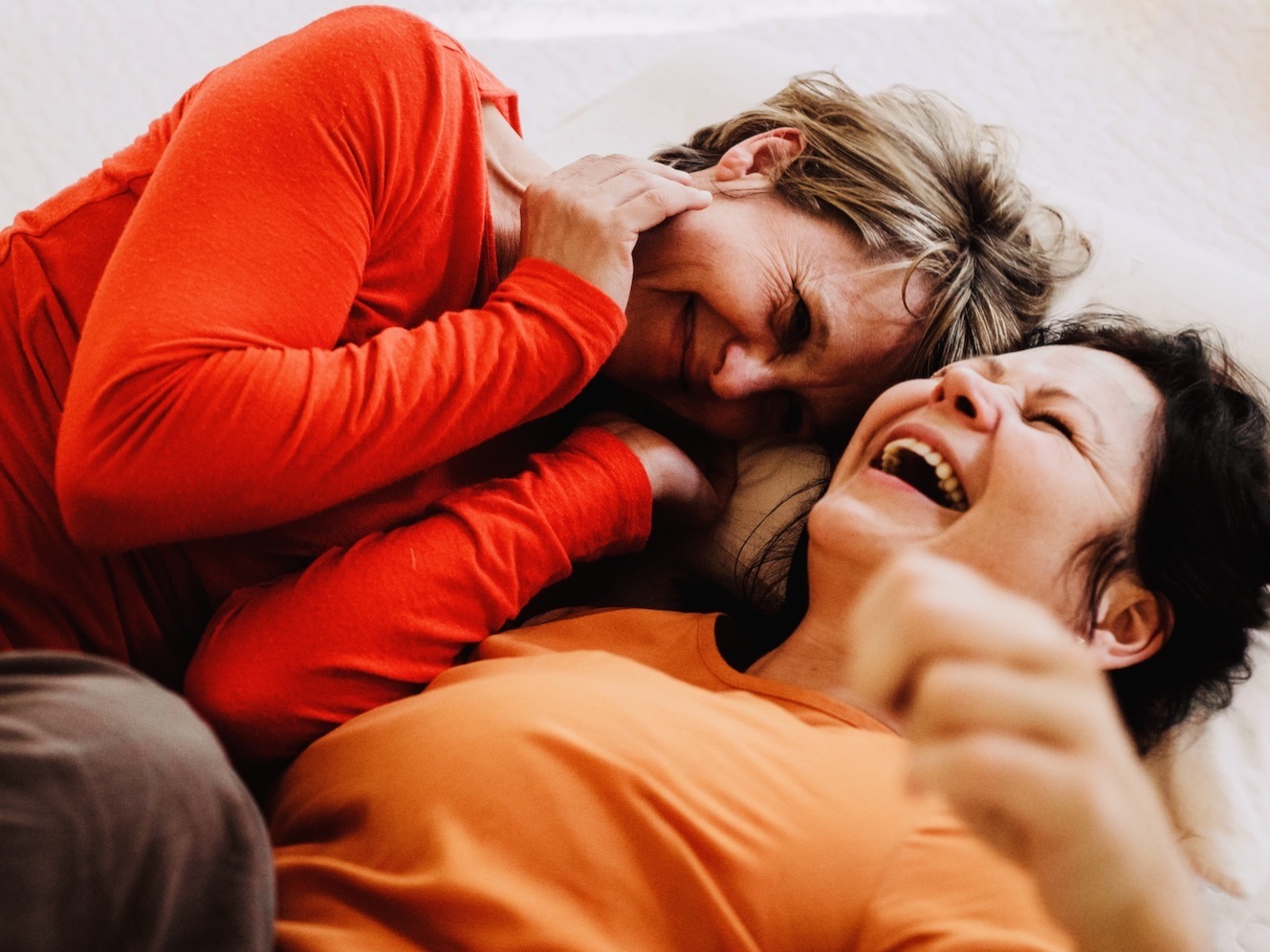 Zwei Frauen kuscheln lachend – achtsame Berührung und Nähe als Ausdruck von Selbstfürsorge
